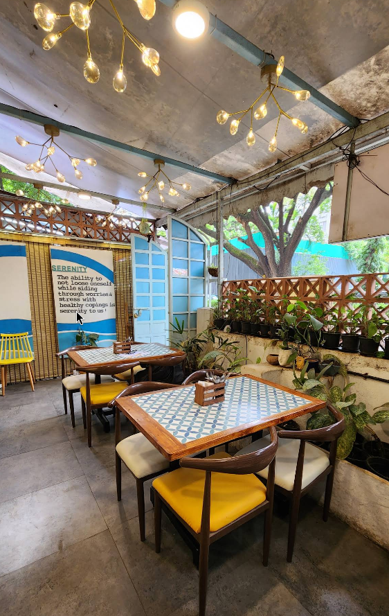 Cafe Serenity's outdoor seating area with beautiful tiled tables, warm lighting, and the Serenity definition on the wall