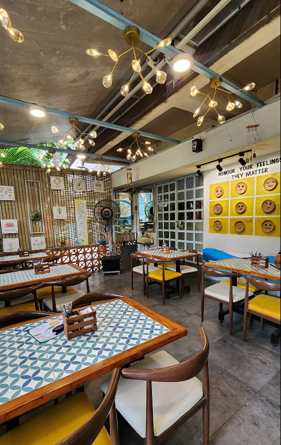 Inside Cafe Serenity — a warm, thoughtfully designed space with mental health awareness decor, cozy wooden furniture, and golden chandelier lighting